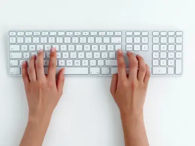 Hands typing on white keyboard