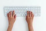 Hands typing on white keyboard