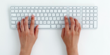 Hands typing on white keyboard