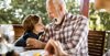 Grandfather smiling at grandson while sitting at a table