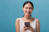Girl holding mobile phone as she smiles looking off to the side