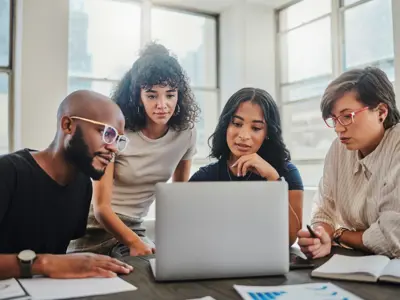 Team working together on a laptop looking at the screen intently