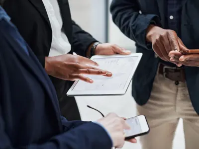 Three office people standing together looking at a tablet