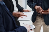 Three office people standing together looking at a tablet