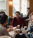 group of five people sitting around a table at a coffee shop